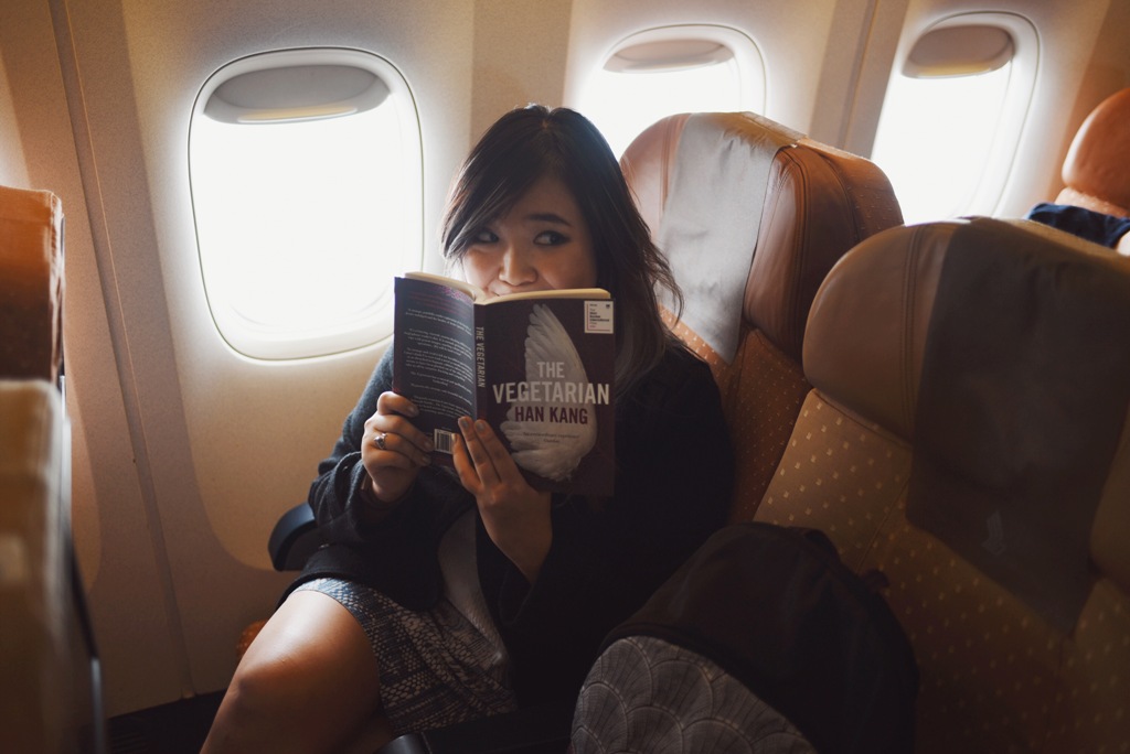 Jemma on a plane with one of her recommendations, The Vegetarian by Han Kang 